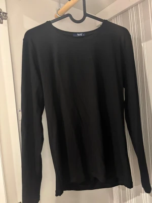 Svart långärmad topp från YCG - En enkel svart långärmad topp från YCG i storlek S. Modellen har rund hals och är tillverkad i mjuk bomull som känns skön mot huden. Perfekt att styla med jeans eller under en jacka för en clean look.