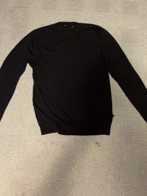 Svart merinoulltröja från Matinique - Svart, stilren tröja från Matinique i storlek L, men sitter mer som M. Tillverkad i 100% merinoull. Rund hals och långärmad modell med ribbade muddar vid hals, ärmslut och nederkant. Perfekt för dig som gillar klassisk och enkel design.