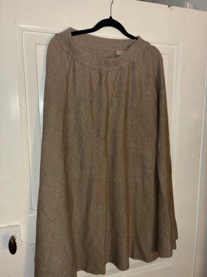 Beige långkjol från Voyelles - Säljer en beige långkjol från Voyelles med ribbad midja och mjukt, stickat material. Kjolen har en lätt utställd form och är perfekt för dig som gillar en enkel men snygg look. Passar till många olika stilar och är superbekväm att bära.