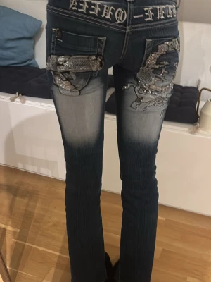 Blue Queen jeans med broderi och paljetter - Säljer ett blue Queen jeans med coola broderade detaljer och paljetter på bakfickorna. Modellen är bootcut med normal passform och lowwaist.