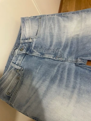 Slim fit ljusblå premiumjeans från Dressman - Slim fit jeans i ljusblå tvätt från Dressman, med klassisk femficksdesign och knappgylf. Jeansen har en snygg faded effekt framtill och raka ben. Perfekt för dig som gillar en clean och modern look och är aldrig använd.