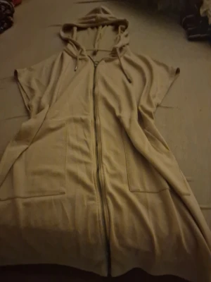 Väldigt lång, beige hoodie - En väldigt lång hoodie som skulle kunna användas som klänning, väldigt skön och baggy vilket ger extra komfort. Passar bra för en kylig Netflix dag med vänner eller partner och lite fika. Jätte söt, passar bra till fredagsmyset. Helt oanvänd, saknar prislapp. Priset som står gäller, kan möjligtvis diskuteras🫶