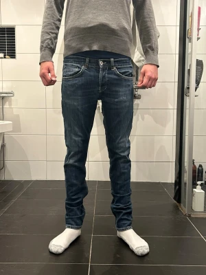 Dondup jeans George  - Snygga blå dondup  jeans med slim fit och klassisk femficksdesign. Jeansen har slitningar och kontrastsömmar, samt dondup logga på bakfickan. Passar dig som gillar en modern och smal siluett. Materialet är slitstarkt jeans i bomull. Storlek 33, passar 32,31