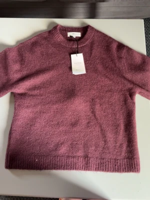 Vinröd stickad tröja - Mysig vinröd stickad tröja från Gina tricot ullblandning. Tröjan har rund halsringning, ribbade muddar och en relaxed passform. Perfekt för kyliga dagar och enkel att styla med olika outfits.