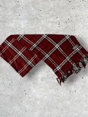 Vinröd Burberry Halsduk - Säljer en snygg vinröd Burberry halsduk med det ikoniska rutmönstret. Tillverkad i 100% mjuk och värmande ull.   🧵 Skick: Mycket fint skick, varsamt använd 🌟 Känsla: Mjuk, varm och följsam 📦 Frakt: Skickas tryggt inom 24h 📏 Mått: Längd-140cm, Bredd-30cm Pris kan diskuteras!