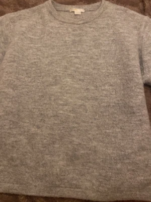 Ljusgrå stickad tröja - Mysig stickad tröja som är kort ärmad! I grå. Den är i storlek 170 men jag har S och den passar mig jätte bra. 