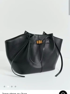 Stor axelväska i skinnimitation - Säljer en stor och rymlig axelväska i skinnimitation med lång rem och snyggt guldfärgat spänne. Finns i både svart och brunt, med minimalistisk design och dekorativa snördetaljer på sidorna. Perfekt för dig som vill ha plats för allt du behöver under dagen.  Båda för 700 eller en för 400kr typ helt oandändna 