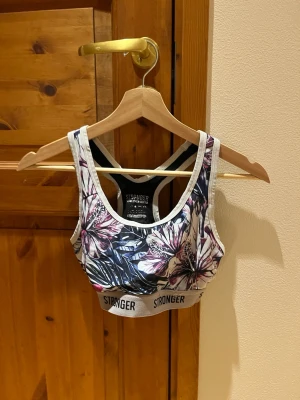 Stronger träningstopp - Träningstopp i storlek XS/S från Stronger. Väl använd men i bra/okej skick. Vissa kan uppleva det nedre bandet något dämpad originalfärg och texten där det står märke och storlek är sliten från tvätt. Finns även en söm som gått upp lite men inget som jag upplever påverkar helhets intrycket av plagget. Bilder finns på slitage, matchande byxor finns!  Färgen är lila/blå/vit i lite djungeltema.  Säljes då den inte längre passar. Djur och rökfritt hem. Pris är diskutabelt.