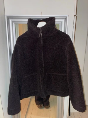 Brun teddyjacka från H&M - Mysig brun teddyjacka från H&M med hög krage och hel dragkedja framtill. Jackan har två stora fickor.