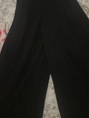 Svarta plisserade byxor från 157 - Säljer ett par svarta plisserade byxor från 157 i storlek S. Byxorna har en loose fit och breda ben, vilket ger en chill och trendig vibe. Materialet är mjukt och stretchigt syntet, perfekt för dig som vill ha både stil och komfort.