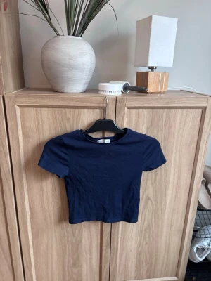 Mörkblå T-shirt - Säljer en mörkblå  topp från Stradivarius i storlek XS. Toppen har rund hals, korta ärmar och är tillverkad i mjuk bomull. 