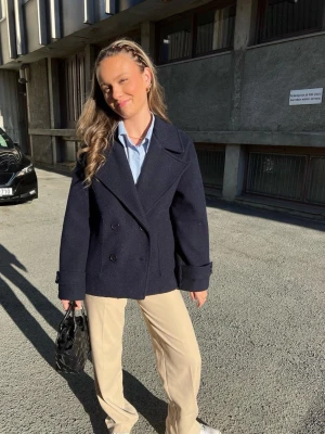 Marinblå kappa med knappar - Säljer en klassisk marinblå kappa med dubbelknäppning och bred krage. Den är mörkblå men kan tolkas som svart i vissa ljus! Nypris 750kr❤️. Onsize, passar mig som vanligtvis bär xs/s men skulle även passa större storlekar!