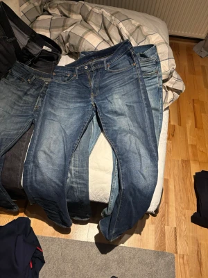 Levi's 502 jeans blå W32 L32 - Säljer ett par Levi's 502 jeans i klassisk blå tvätt med snygga slitningar. Modellen har rak passform och normal midja, med fem fickor och orangea sömmar. Materialet är robust denim i bomull. Perfekt för dig som gillar en tidlös jeansstil.