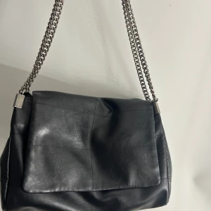 Väska - Super snygg svart skinn väska med silver kedja från Zara. Väskan har mycket utrymme, med 4 olika delar, relativt nyskick då den är använd fåtal gånger 🌸