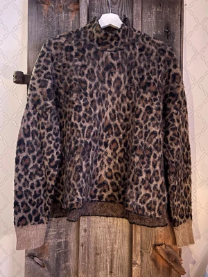 Leopardmönstrad polotröja Second Female - Säljer en snygg leopardmönstrad polotröja från Second Female i storlek L. Tröjan har hög hals och är stickad i en mjuk mix av nylon, ull och alpacka. Färgerna går i brunt och beige med mörka detaljer. Perfekt för dig som vill ha en cool statement-tröja.