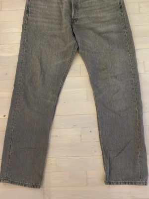 Grå loose fit jeans från Jack & Jones - Säljer ett par grå jeans från Jack & Jones med loose fit och raka ben. Jeansen har klassisk femficksdesign, bälteshällor och knappgylf. Materialet är slitstarkt denim i bomull och färgen är en snygg, tvättad grå nyans.