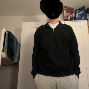 Svart half zip tröja i bomull - Svart långärmad tröja med half zip-dragkedja i halsen. Tröjan har en avslappnad passform och är gjord i mjuk bomull, perfekt för chill dagar. Enkel och stilren design utan tryck eller mönster.