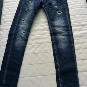 Mörkblå skinny jeans Alessandro Zavetti - Snygga mörkblå skinny jeans från Alessandro Zavetti med slitningar och färgstänk för en trendig look. Jeansen har klassisk femficksdesign och tydliga slitdetaljer framtill. Perfekta för dig som gillar streetstyle och vill sticka ut.