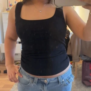 Svart ärmlös linnetopp - Säljer en svart, stilren linnetopp med fyrkantig halsringning och ärmlös design. Toppen har en tight passform och är gjord i mjukt material som sitter skönt mot kroppen. Perfekt att matcha med jeans eller kjol för en enkel och snygg look.