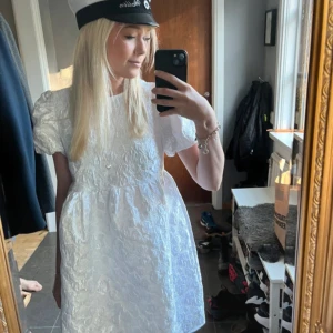 Vit kort klänning med puffärm - Supersöt vit kort klänning med puffärmar och strukturmönster i tyget. Jag hade den som studentklänning så endast använd 1 gång⭐️💞