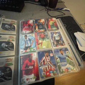 Samlaralbum med fotbollskort - Ett samlaralbum fyllt med fotbollskort från kända spelare som Lionel Messi, Henrik Larsson och Sergio Agüero. Perfekt för dig som älskar fotboll och vill ha en cool samling att visa upp eller byta med vänner. Flera limited edition-kort och klassiska spelare från Champions League och landslag.