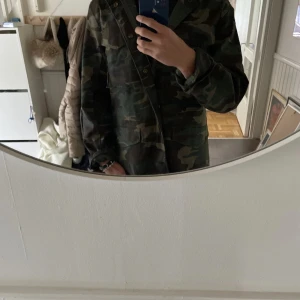 Camouflagejacka från Brandit - Säljer en cool camouflagejacka från Brandit med avtagbart innerfoder. Jackan har en klassisk militärlook med dragkedja och knappar framtill. Perfekt för utomhusaktiviteter och har en praktisk design med flera fickor och mycket detaljer. Jackan är sprillans ny och helt oanvänd! Hör av er om ni har frågor eller om ni vill byta något😇