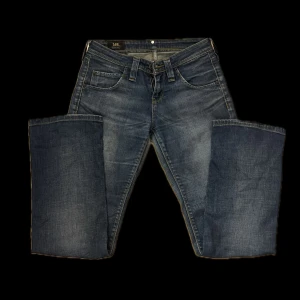 Blå Lee jeans - Snygga blå jeans från Lee med klassisk femficksdesign. Jeansen har gul kontrastsöm och Lee-logga på bakfickan. Materialet är slitstarkt denim och passformen är normal. Perfekt för dig som gillar en tidlös jeanslook.