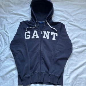 GANT Ziphoodie - Mörkblå ziphoode från Gant i storlek S. Den användes mycket för något år sen men är fortfarande i bra skick!🙌 Personligen tycker jag den är riktigt fet och tveka inte på att höra av er vid minsta fundering eller annat!✌️