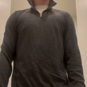 Mörkgrå stickad half zip tröja - Snygg mörkgrå stickad tröja från Jack and Jones  med half zip-dragkedja i halsen. Tröjan har långärmad design och är tillverkad i mjukt material som ger en chill och stilren look. Perfekt för dig som gillar klassisk stil med modern touch.