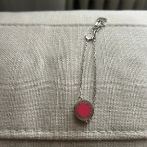 Silverfärgat armband från Marc by Marc  - Snyggt armband i silverfärg med tunn kedja och rund bricka i rosa. På brickan står Marc by Marc ingraverat runt kanten. Perfekt för dig som gillar stilrena smycken med en pop av färg.