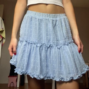 Ljusblå volangkjol🩵 - Supersöt ljusblå kortkjol med volanger och små prickar. Kjolen har ett tunt, transparent yttertyg med volangdetaljer och ett mjukt underkjol i samma färg. Perfekt för dig som gillar en fin kjol till våren eller sommaren✨