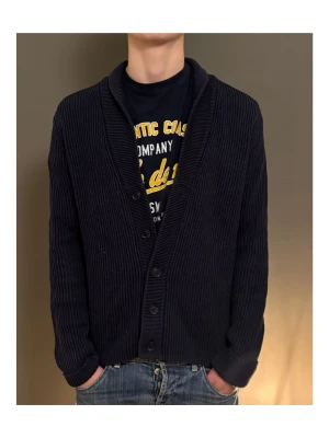 Mörkblå ribbstickad kofta - Säljer en mörkblå ribbstickad kofta med knappar framtill och bred krage. Koftan har lång ärm och en klassisk, lite loose passform. Perfekt att slänga på sig över en t-shirt för en chill look.