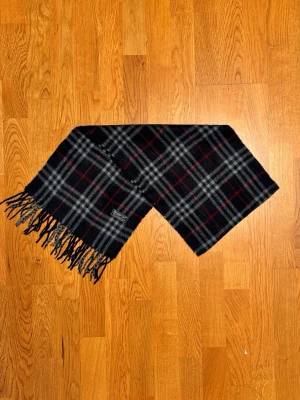 Mörkblå Burberry halsduk - Säljer en mörkblå halsduk från Burberry. Halsduken är gjord i lamull och är i gott skick. Var inte rädd för frågor. Pris diskuteras inte!