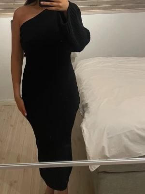 Svart stickad oneshoulder långklänning - Säljer en svart, ribbad stickad långklänning med oneshoulder-design💕 Stilren och perfekt nu inför vintern 💕 