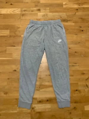 Grå mjukisbyxor från Nike - Snygga klassiska grå mjukisbyxor från Nike med två fickor och en bakficka. Den är i gott skick och har inga synliga skador. Hör av dig vid funderingar!