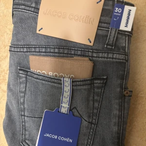 Jeans från Jacob Cohën - Snygga grå jeans från Jacob Cohën med klassisk femficksdesign och subtilt broderad J på myntfickan. Jeansen har en stilren look med mörkgrå tvätt och detaljerade sömmar. Materialet är mjukt jeans-tyg och passformen är normal. Perfekt för dig som gillar exklusiva märken. 5500kr nypris. Dessa är helt nya och inte använda och väldigt exklusiva hör av dig vid minsta fundering.
