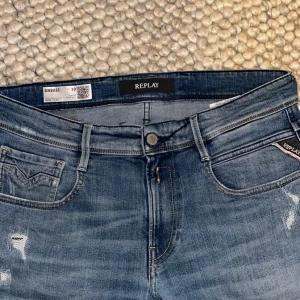 Replay Anbass  - Säljer ett par Replay Anbass jeans i blå tvätt med slitningar och hål för en cool, avslappnad look.  klassiska fem fickor och knappgylf. Perfekta för dig som gillar streetstyle och vill ha jeans med attityd. PRIS KAN DISKUTERAS 
