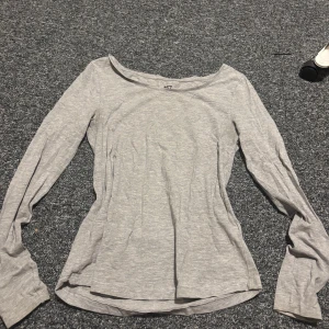 Grå långärmad topp från 157 - Säljer en enkel och stilren grå långärmad topp från 157 i storlek M. Toppen har en rundad halsringning och är gjord i mjuk bomullsmix med viskos och elastan för extra komfort. Perfekt att matcha med jeans eller kjol.