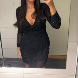Svart klänning ohpolly - Endast använd en gång, fint skick men vissa av ”kulorna” har lossnat. Den har en insydd body under klänningen.  Storlek us 4. Mindre i storleken, skulle säga att den känns som en svensk xs. Men passar mig som brukar ha xs eller s. Jag är 165cm lång.  Nypris är 1 520kr. Från ohpolly.