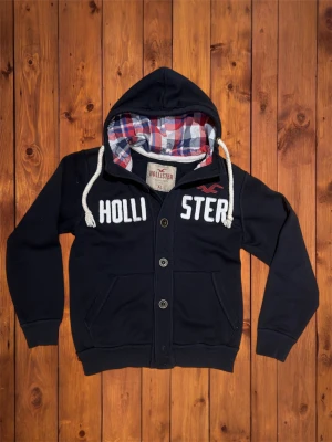 Vintage Hollister Hoodie (sällsynt) - Säljer denna vintage, sällsynta och asfeta hoodien/cardiganen från Hollister. Den är riktigt fet och har snygg design på framsidan. Storlek är XL men den passar som M. Hör av er vid funderingar och se måtten nedan. B=68cm A=57cm 