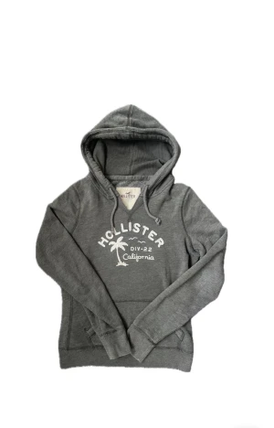 Vintage Hollister hoodie (Sällsynt) - Säljer nu denna sjukt snygga och eftertraktade hoodie från hollister med ett unikt tryck😊 Säljs ej längre i butik och är därför sällsynt 🙌 Storlek L på etiketten men den passar S-M bättre! Skriv vid funderingar eller prisförslag 📲🤝