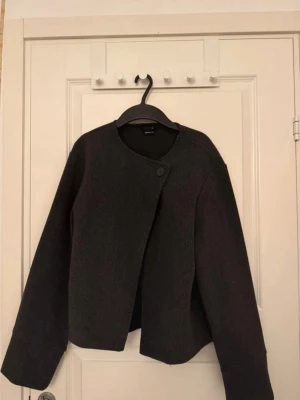 Svart kappa från Gina Tricot XS - Säljer en stilren mörkgrå kappa från Gina Tricot i storlek XS. Den är helt oanvänd och köpt från förra året så tror ej denna går att få tag på längre. Pris kan diskuteras 🤍