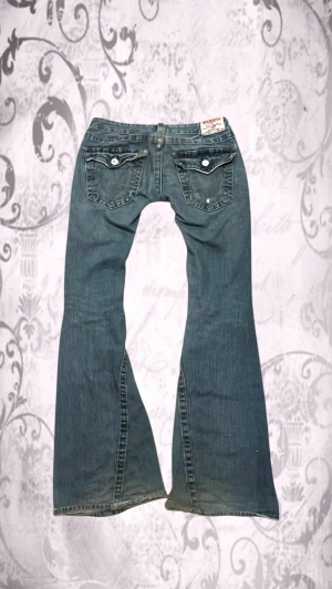 Blå bootcut jeans från True religion - True Religion jeans i Bootcut/Flared modell med slitningar!💗W30, 38 cm rakt över midjan och 86 cm innerbenslängd 😊 Hör av er om ni har några frågor!