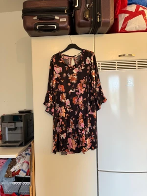 Odd Molly blommig kortklänning - Supersöt kortklänning med svart botten och blommigt mönster i rosa, orange och beige toner. Klänningen har volangdetaljer på ärmarna, rund hals med liten öppning bak och långa ärmar. Perfekt för dig som gillar boho-vibe och färgglada prints. Från märket Odd Molly. Storlek 2 som enligt deras storleksguide motsvarar en M. Mycket fint skick, jag hittar inga synliga anmärkningar eller defekter.  