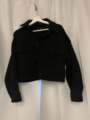 Svart kappa - Jätte fin kappa i kortare modell. Knappar och stora fickor där fram. Märket är stradivarius i storlek xs 