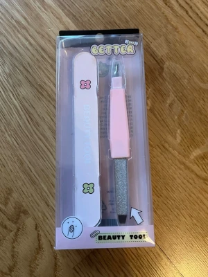 Nagelfilset Beauty Tool rosa - Nagelfilset med två delar i söt rosa design. Ena filen har blommor och texten 'Beauty Tool', den andra har ett rosa handtag och en glittrig filyta. Perfekt för att fixa naglarna hemma eller på språng.