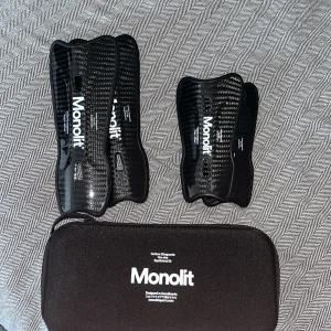 Monolit benskydd i kolfiber - Säljer två par svarta Monolit benskydd i kolfiber, superlätta och tåliga med snyggt kolfibermönster. Kommer inte med fodral. Perfekta för dig som vill ha maxad komfort och skydd på planen. One size. Kom med bud. Kan lösas snyggt vid en snabb affär. 