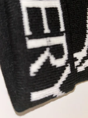 Svart mössa från Arc'teryx - Svart mössa från Arc'teryx med vit logotyp och text. Stickad i mjukt material och har en klassisk passform. Perfekt för kalla dagar och snygg detalj med det ikoniska Arc'teryx-skelettet framtill.