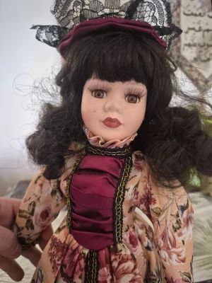 Viktoriansk stil samlarminnen, 45cm porslinsdocka, rubinbruna ögon, svart hår - En vacker porslinsdocka med detaljerad klänning och matchande hatt. Dockan har mörkt hår och en liten handväska. Perfekt för samlare eller som en dekorativ inredningsdetalj.