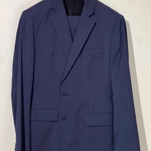 Marinblå kostym från J. Lindeberg - En marinblå kostym från J. Lindeberg som har använts ett fåtal gånger. Storlek kavaj: 52R (regular). Storlek byxor: 50. Säljes eftersom jag har vuxit ur den. 